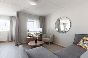 Un salon moderne avec un téléviseur à écran plat, un miroir rond, un canapé et une table basse.