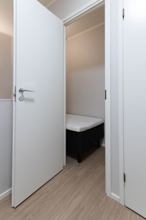 A white door with a silver handle, leading to a room with a mattress on the floor. - Stylish 2-bedroom family apartment w/ sauna, parking (Helsinki)
