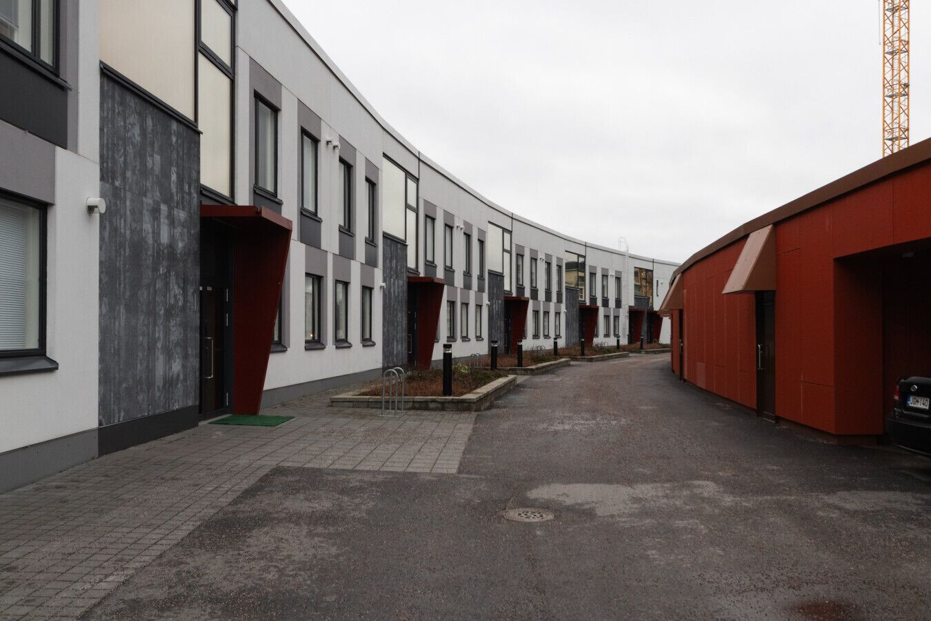 Un edificio moderno con fachada curva, múltiples ventanales y zona de estacionamiento.