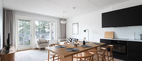 A modern kitchen with a dining area, large windows, and a view of the outdoors.