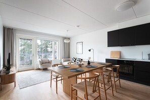 A modern kitchen with a dining area, large windows, and a view of the outdoors.