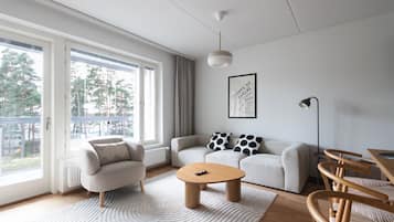 Moderni olohuone, jossa on sohva, nojatuoleja, sohvapöytä ja ruokailutila tuoleineen.