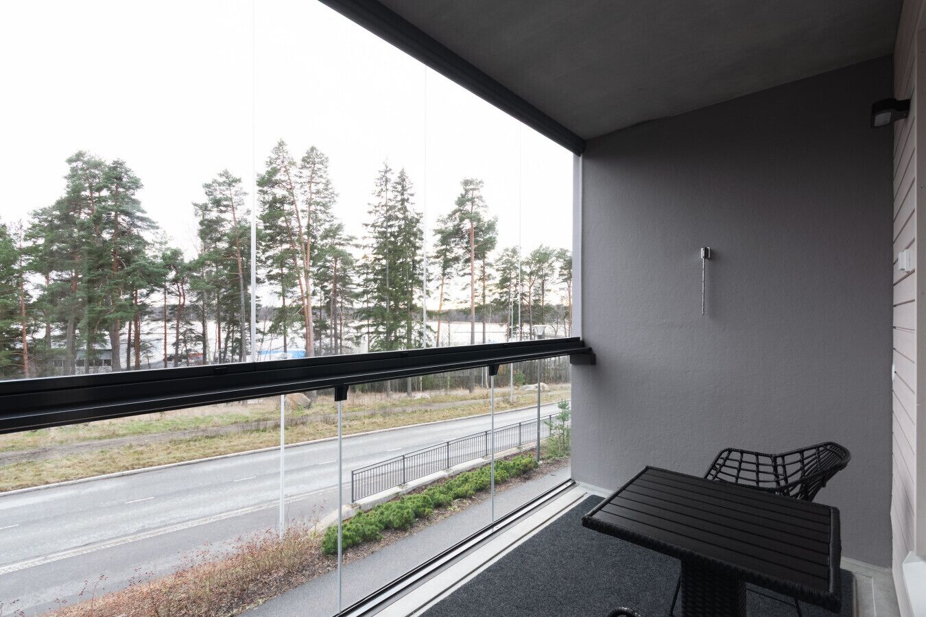 Parveke, josta on näkymä kadulle ja puille, pieni pöytä ja tuoli.