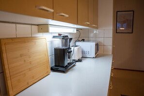 Una cocina con cafetera, microondas y armarios de madera.