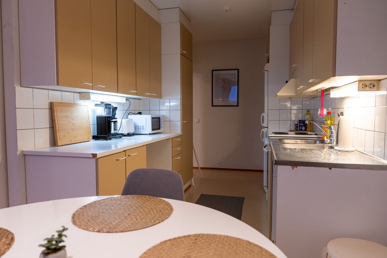 A compact kitchen with a dining area, featuring a microwave, coffee maker, and a small sink.