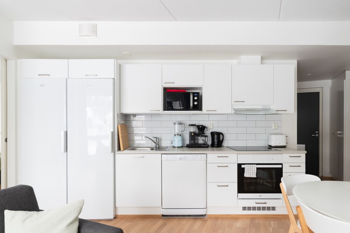 A compact kitchen with white cabinetry, a microwave, a coffee maker, and a dishwasher.