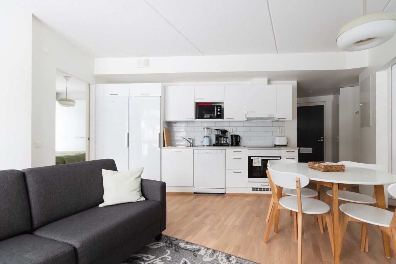 Moderni keittiö, jossa on valkoiset kaapit, mikroaaltouuni ja kahvinkeitin.