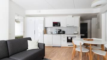 Moderni keittiö, jossa on valkoiset kaapit, mikroaaltouuni ja kahvinkeitin.
