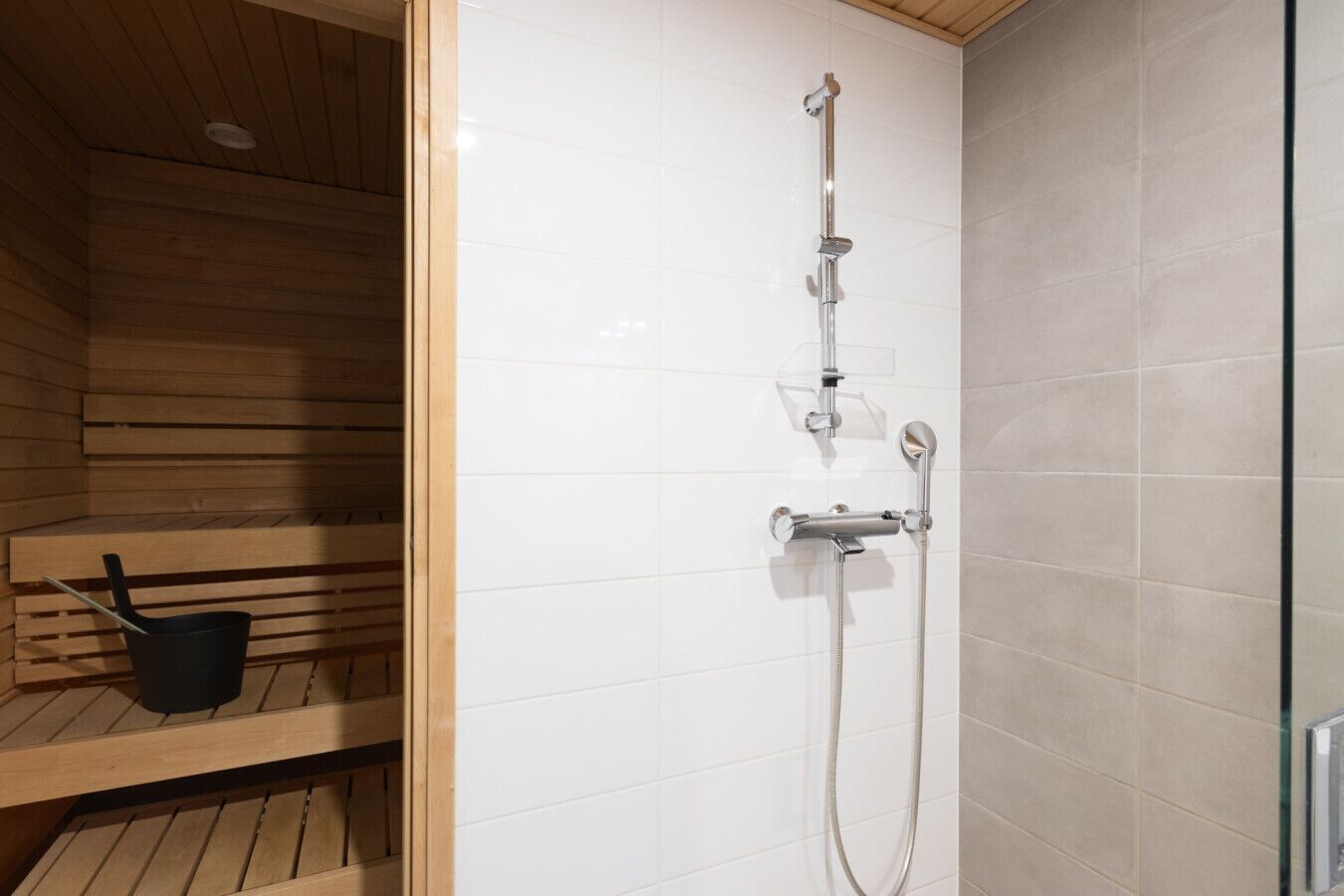 Uma sauna com banco de madeira e um balde preto.