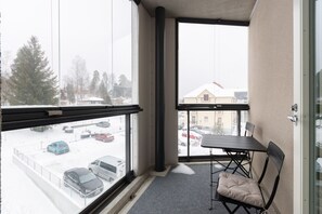 Un balcon donnant sur un parking enneigé et des immeubles.