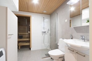 Moderni kylpyhuone, jossa on suihku, wc ja pesuallas.