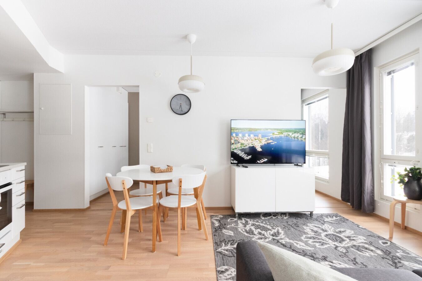 Un espacio habitable moderno con comedor, televisor de pantalla plana y vista a un cuerpo de agua.