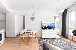 A modern living space with a dining area, a flat-screen TV, and a view of a body of water. - Family apartment with parking, sauna balcony for 6 (Jyväskylä)