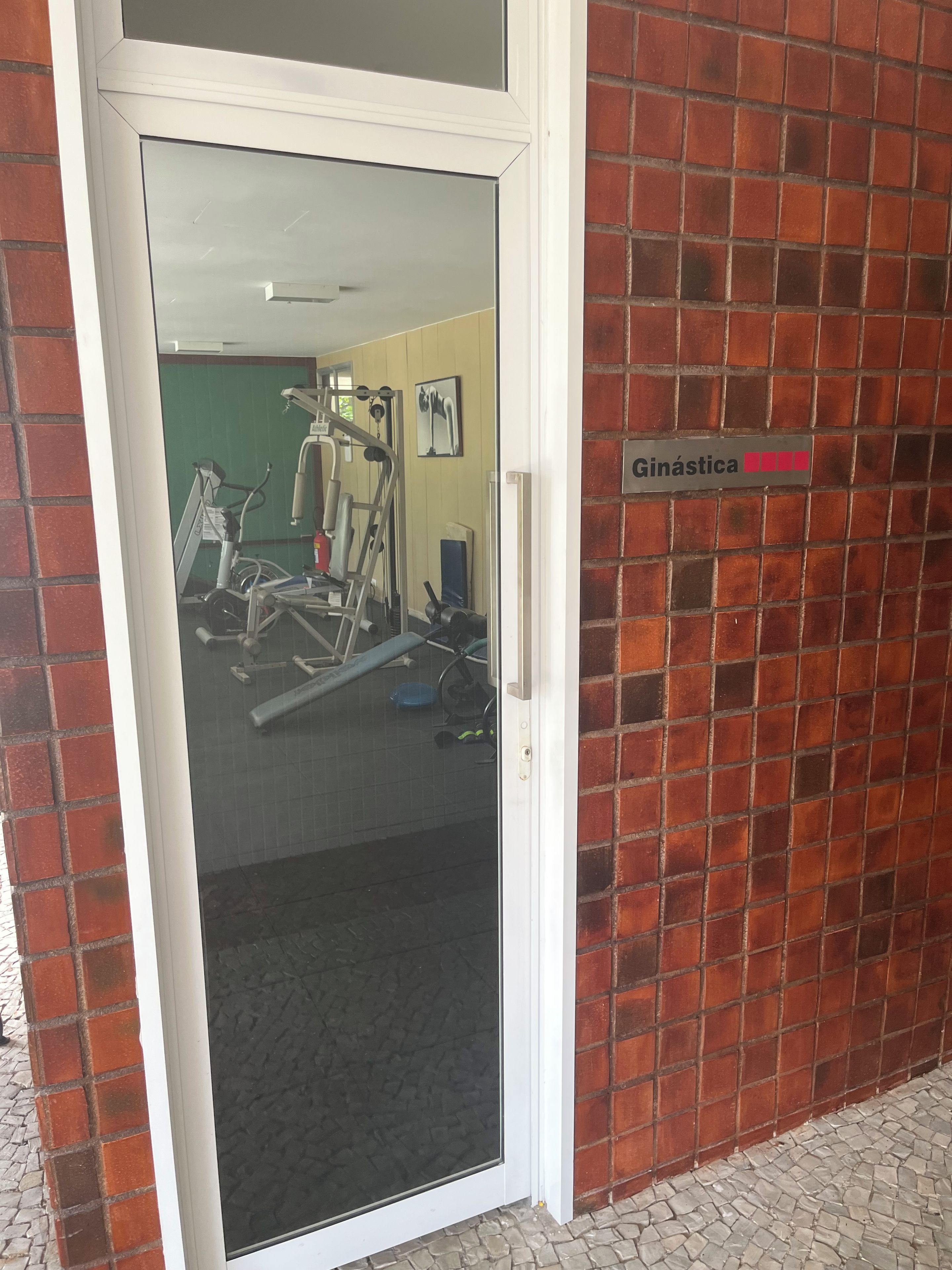 Een deur met een bord waarop 'Ginástica' staat, wat een sportschoolzone aangeeft.