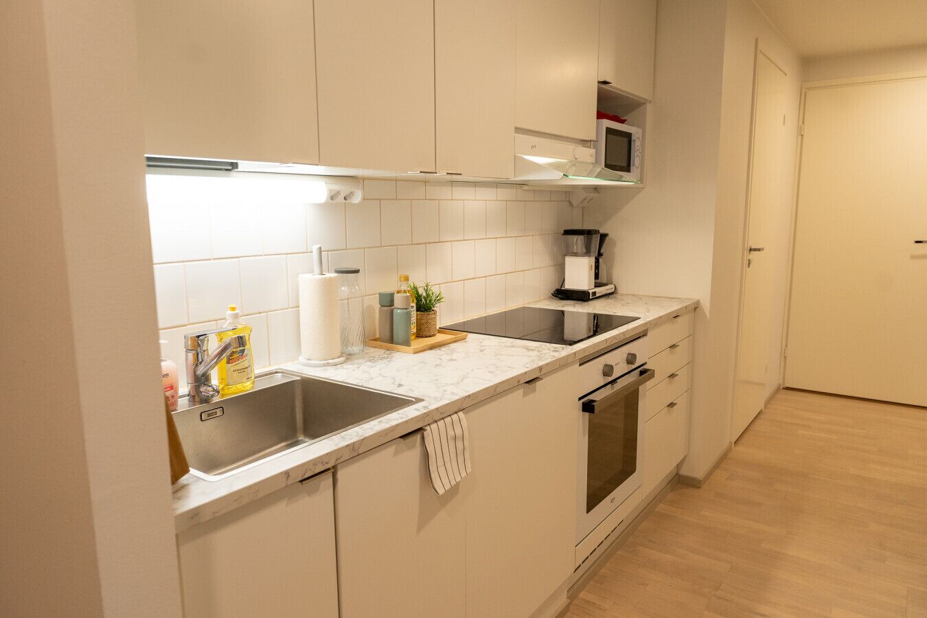 A modern kitchen with a double sink, a microwave, a coffee maker, and a built-in oven.