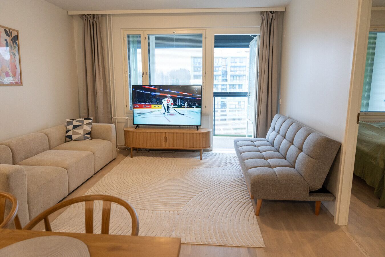 Een woonkamer met een televisie, twee banken, een houten salontafel en een vloerkleed met een patroon.