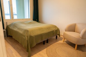 Une petite chambre à coucher agréable, avec un lit simple, une chaise et une fenêtre équipée de stores.
