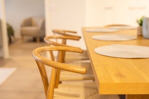 Une table de salle à manger en bois, agrémentée de sets de table ronds blancs et de chaises en bois assorties.