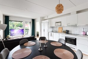 Una cocina moderna con armarios blancos, un microondas y una licuadora rosa.