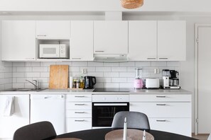 Eine moderne Küche mit weißen Schränken, einer Mikrowelle, einer Kaffeemaschine und einem Toaster.