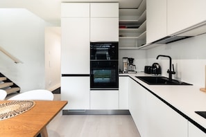 Una cucina moderna con mobili bianchi, un forno nero, una macchina da caffè e un rubinetto nero.