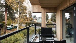 A balcony with a glass table and chairs, overlooking a residential area with trees and parked cars. - Brand new house with four bedrooms, parking, sauna, patio (Vantaa)