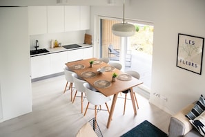 Una cucina moderna con mobili bianchi, un piano di lavoro nero e una zona pranzo con tavolo in legno e sedie bianche.