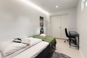 Quarto com uma cama, uma escrivaninha e um guarda-roupa.