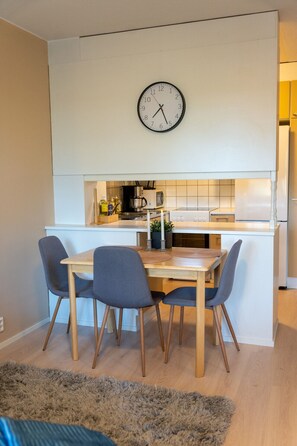 Een moderne keuken met een eethoek, met een klok, houten stoelen en een kleine tafel.