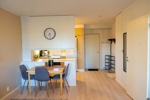 Eine kleine Küche mit Essbereich, einer Uhr an der Wand und einer Tür zu einem weiteren Zimmer.