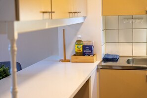 Eine Küche mit weißer Arbeitsplatte, einem hölzernen Hocker, einer Olivenölflasche und einer Pastapackung.