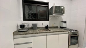 A compact kitchen with a sink, stove, and microwave. - 2802 Parc Apto 3 qtos Luxo com Garagem (Belém)