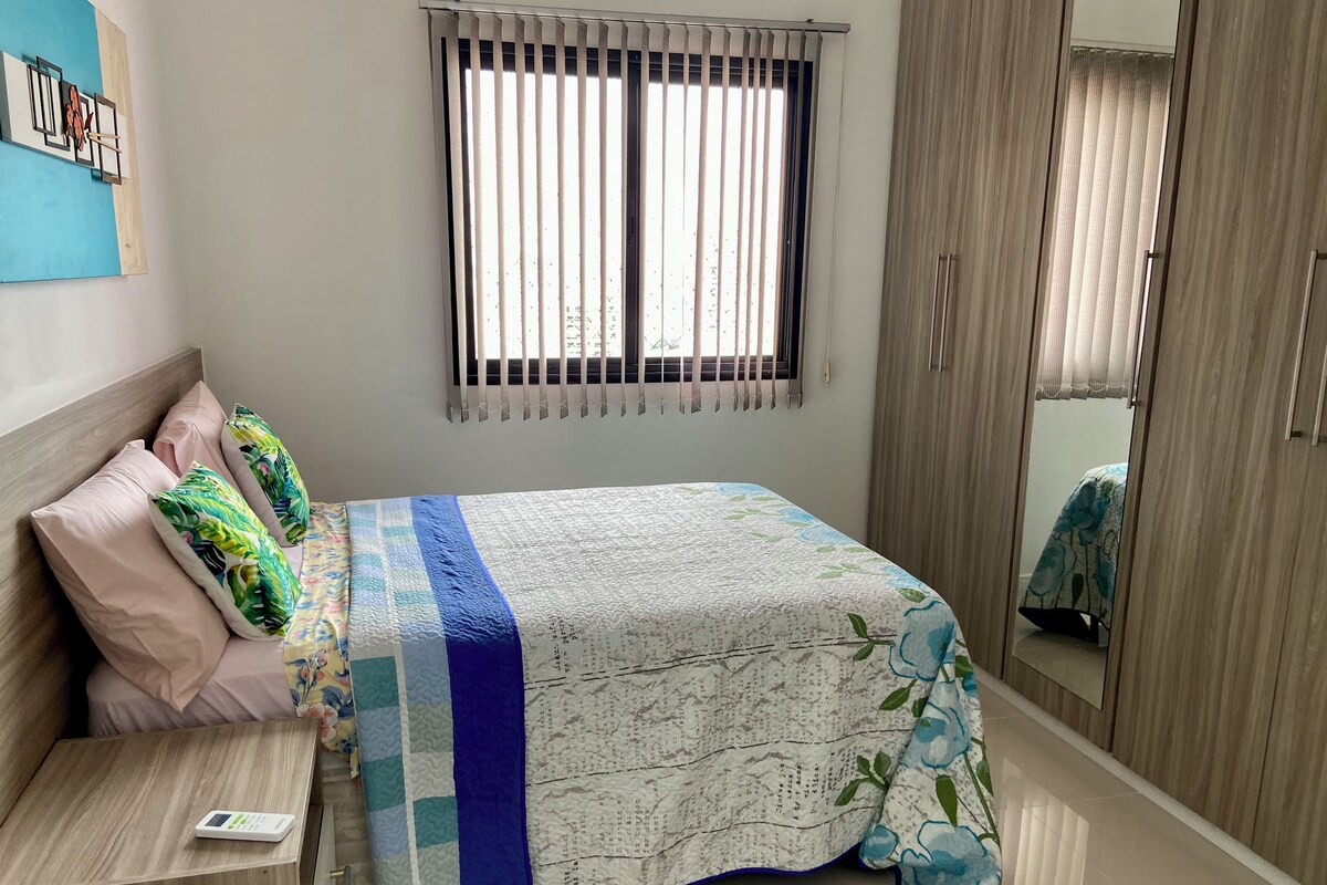 Un dormitorio con una cama, una mesita de noche, un armario y una ventana con persianas.