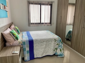 Un dormitorio con una cama, una mesita de noche, un armario y una ventana con persianas.
