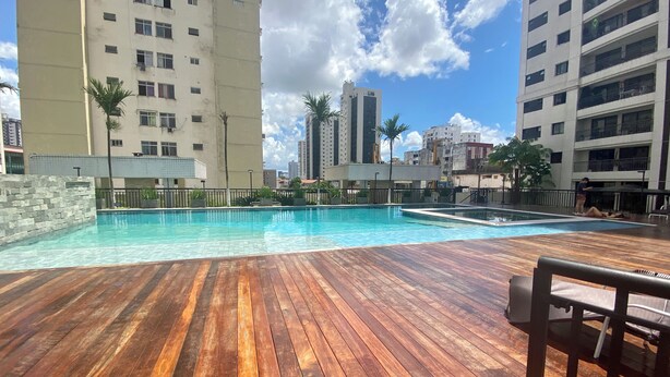 A swimming pool with a wooden deck, surrounded by tall buildings. - 2802 Parc Apto 3 qtos Luxo com Garagem (Belém)