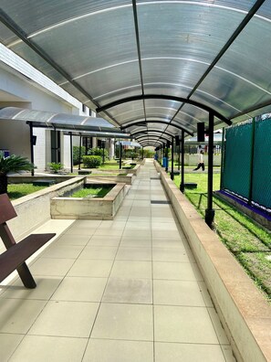 A covered walkway with tiled flooring, planters, and a fence on one side. - 2802 Parc Apto 3 qtos Luxo com Garagem (Belém)