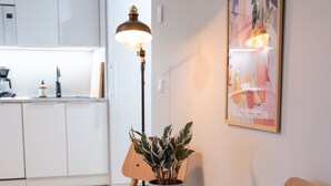 A modern kitchen with white cabinets, a round wooden table with a potted plant, and a chair. - Beautifully furnished family apartment - parking, sauna, balcony (Jyväskylä)