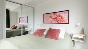 A bedroom with a bed, a bedside table, a nightstand, a mirror, and a wall-mounted picture. - Beautifully furnished family apartment - parking, sauna, balcony (Jyväskylä)