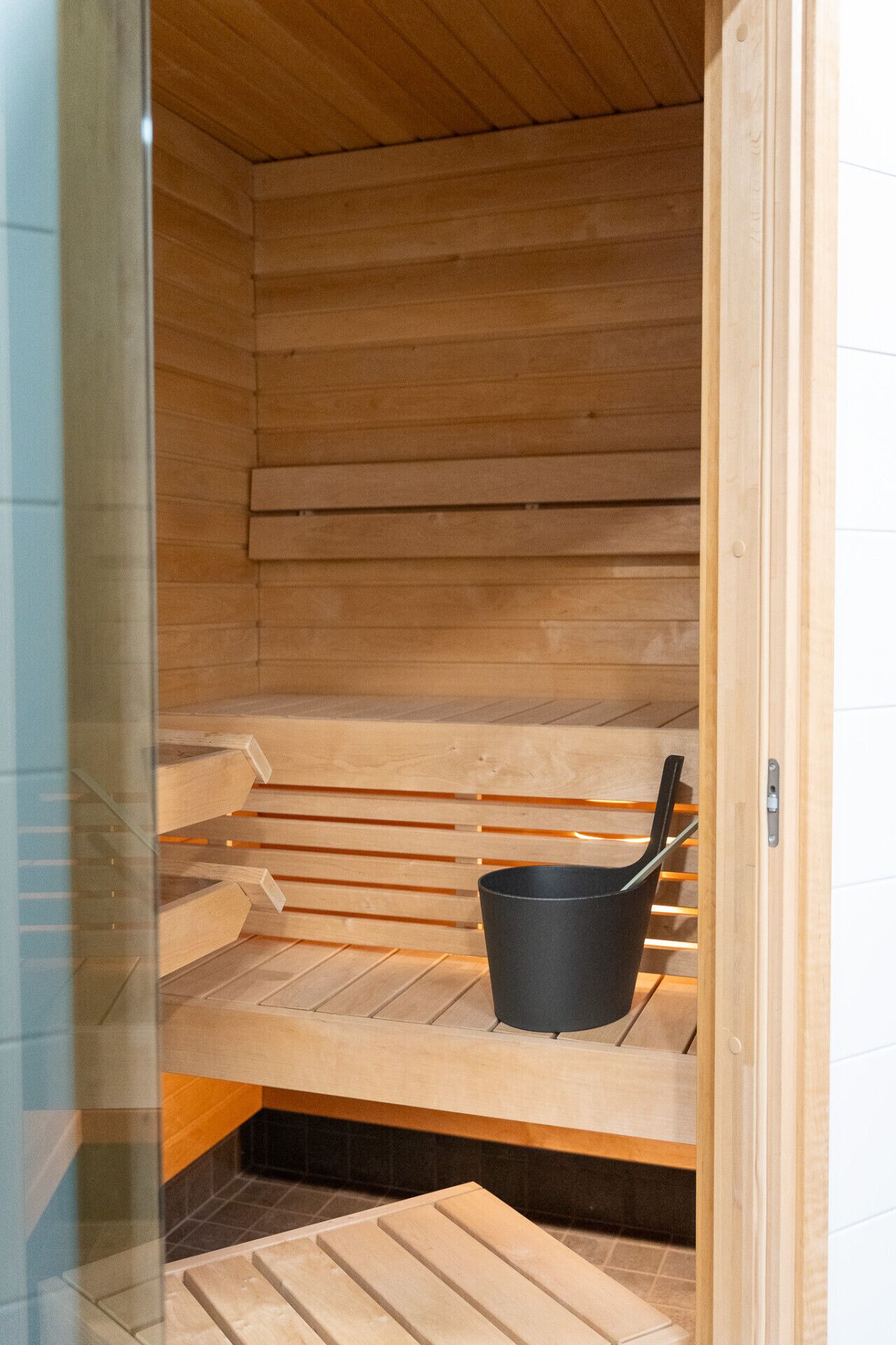 A sauna with wooden benches and a black bucket.