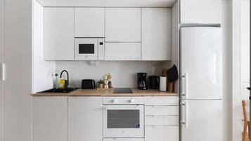 Una cucina moderna con mobili bianchi, un forno a microonde, una macchina da caffè e un frigorifero.