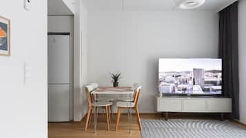 Moderni olohuone, jossa on ruokailutila, sisäänrakennettu televisio ja näkymä kaupunkimaisemaan.