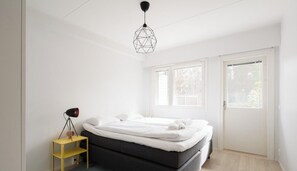 A bedroom with a bed, a lamp, and a window.