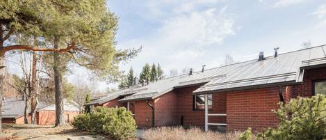 A red brick building with a metal roof, surrounded by trees and shrubs.