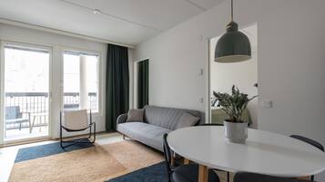 Una sala de estar moderna con sofá, mesa de comedor y planta en maceta.