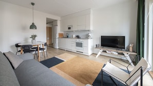 Un apartamento moderno con sala de estar, comedor, kitchenette y televisor.