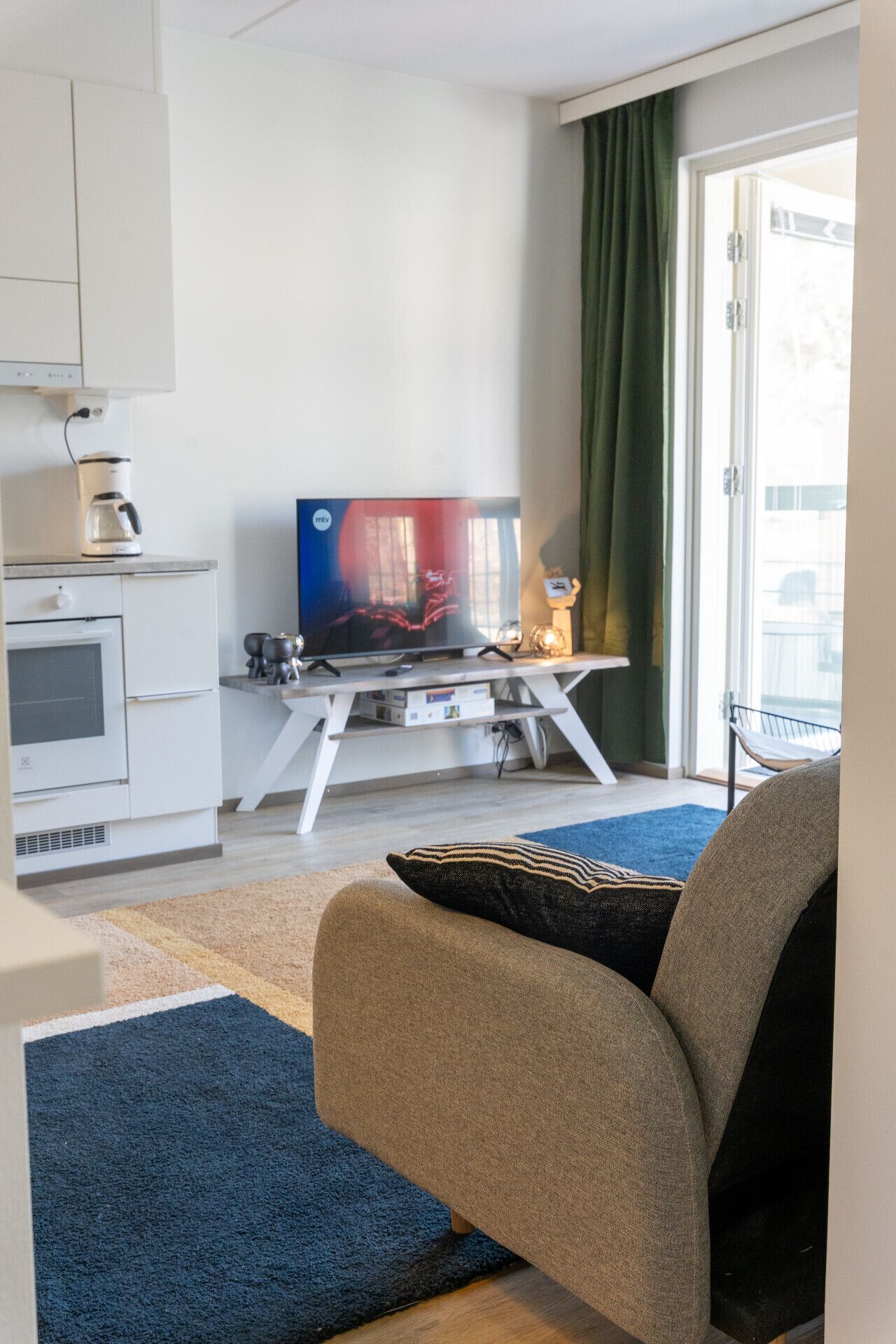 A modern living room with a flat-screen TV, a coffee maker, and a sofa.