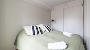 Una habitación con cama, almohadas, lámpara y armario.