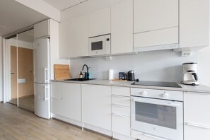 Eine moderne Küche mit weißen Schränken, einer eingebauten Mikrowelle, einer Kaffeemaschine und einem Toaster.