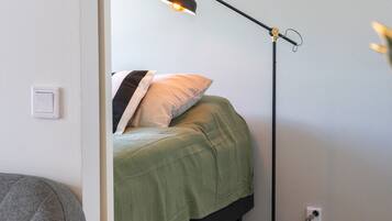 Una habitación con cama, escritorio, silla y lámpara de pie.