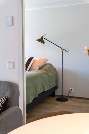 Een kamer met een bed, een bureau, een stoel en een vloerlamp.